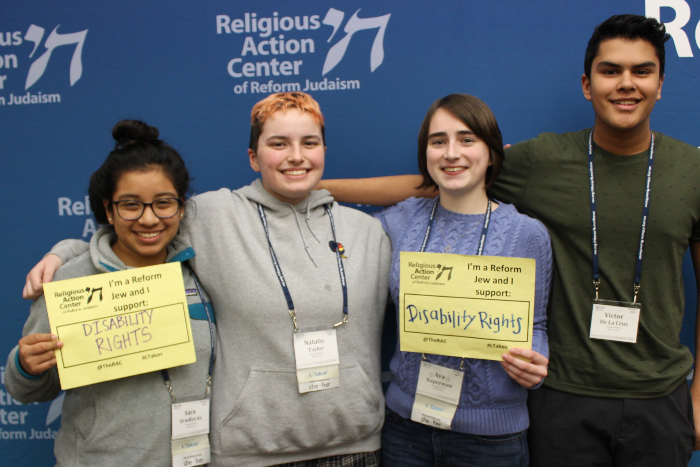 Four teens holding signs that say I AM A REFORM JEW AND I SUPPORT DISABILITY RIGHTS