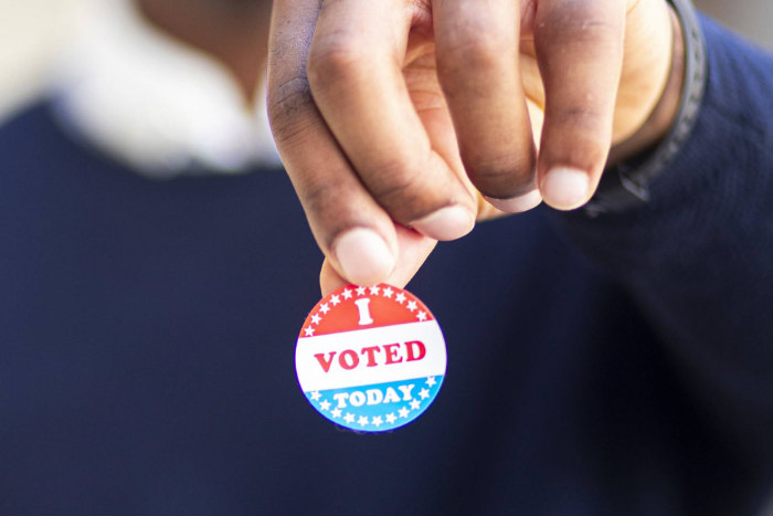 Hand holding a sticker that says I VOTED TODAY