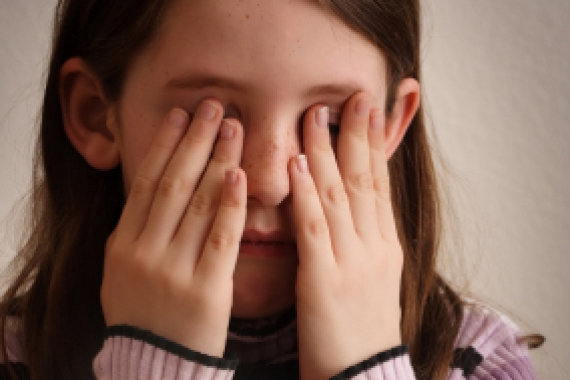 Girl covering her eyes while blessing the candles